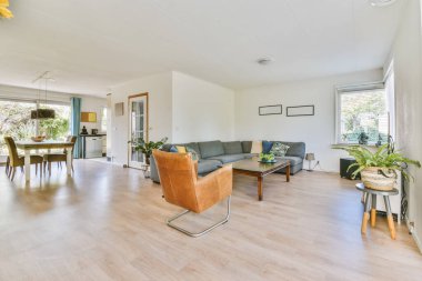 Odanın ortasında ahşap döşemeli ve beyaz duvarlı bir oturma odası yemek masası, iki sandalye ve bir...