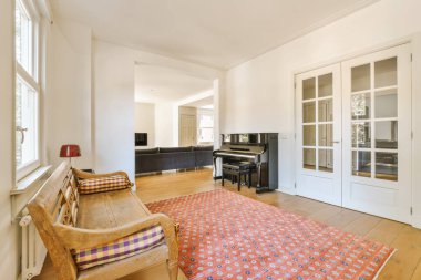 a living room with white walls and hardwood flooring, including a piano in the middle part of the room