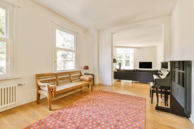 a living room with hardwood flooring and an old piano in the area is well lit by the large windows
