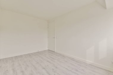 Beyaz duvarları ve ahşap zemini olan boş bir odanın içinde.