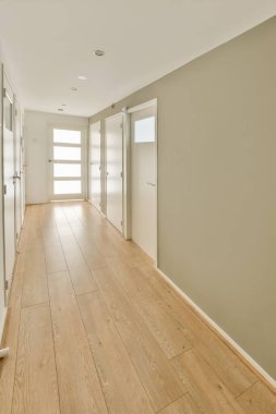 Bu fotoğrafta duvarlarında ahşap döşeme ve beyaz süsleme olan boş bir oturma odası sağa doğru çekiliyor.