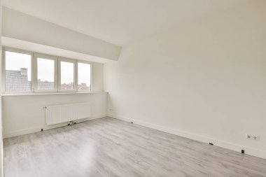 Beyaz duvarları ve ahşap zemini olan boş parlak bir oda.