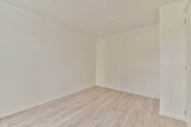 Beyaz duvarları ve ahşap zemini olan boş bir odanın içinde.