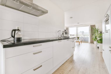 Günümüz minimalist tasarımı. Hafif stüdyo dairesinin ahşap masası ve oturma odası ile beyaz duvarları ve parke zemini arasında yemek masası ve sandalyeleri var.