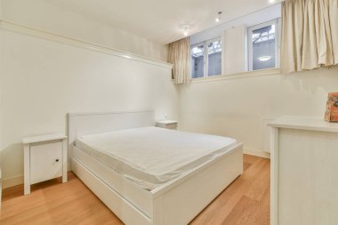 Beyaz çift kişilik yataklı ve beyaz ahşap mobilyalı bir yatak odası.