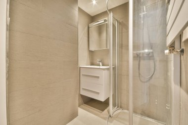 Duş kabini, lavabosu ve aynası olan modern banyo.