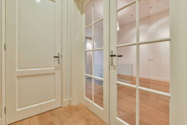 Beyaz ahşap kapısı ve büyük cam kapısı olan parlak koridor.