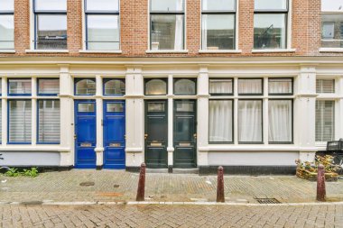 Dışarısı mavi kapılı ve pencereli tuğla bir bina, hemen yanına park edilmiş bir bisikletin önünde.