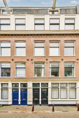 Amsterdam 'da eski bir tuğla bina. Önünde mavi kapılar ve pencereler var. Evinize girebilmeniz için.