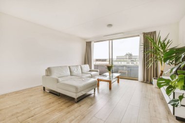 Günümüz minimalist tasarımı. Hafif stüdyo dairesinin ahşap masası ve oturma odası ile beyaz duvarları ve parke zemini arasında yemek masası ve sandalyeleri var.