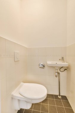 Lavabolu ve duvarlı, beyaz duvarlı ve kareli tuvaletli dar bir tuvalet.