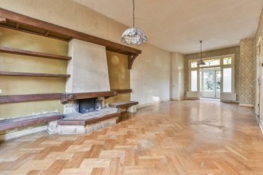 Bir şömine seti ve duvardaki raflar yarım duvar kağıtlı boş bir odada.