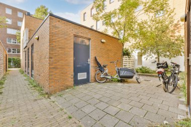 Binanın duvarına yaslanmış bisikleti olan tuğla bir binanın önüne park etmiş bir bisiklet.