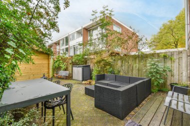 Bir masa, sandalyeler, kanepe ve evin bahçesinde bir bank.