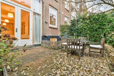 Evin güzel yeşil bahçesinde ahşap masa ve sandalyeler.