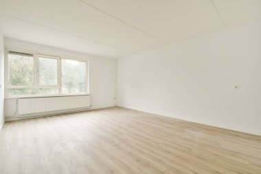 Geniş pencereli parlak ve havadar boş bir oda, dekorasyon veya dönüşüm için ideal temiz ve minimalist bir iç mekan sergiliyor..