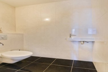 Pürüzsüz fayanslardan oluşan temiz ve çağdaş bir banyo, minimalist bir tasarım ve bol miktarda doğal ışık, dinlenmek için sakin bir ortam yaratıyor..