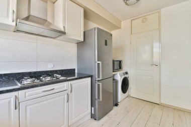 Zarif dolaplar, paslanmaz çelik bir buzdolabı ve parlak bir zemin üzerine kurulmuş modern aletlerin yer aldığı şık ve çağdaş bir mutfak..