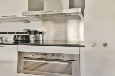 Gösterişli aletlerin, minimalist tasarımın ve temiz estetiğin bulunduğu çağdaş bir mutfak. Modern elementlerin kombinasyonu işlevselliği ve tarzı geliştirir..