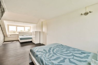 Geniş, modern bir yatak odası, iki yatak odası, parlak mobilyalar, ve doğal ışığın odayı aydınlatmasına izin veren büyük pencereler..