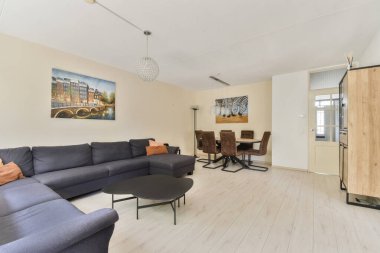 Şık bir kanepe, dekoratif bir tablo ve yemek odası olan, çağdaş tasarım ve konfor sergileyen rahat bir modern oturma odası..