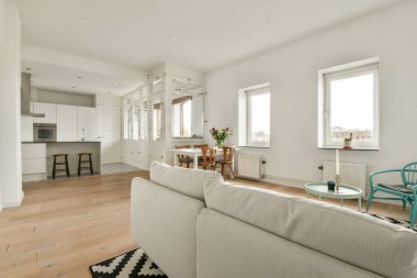 Doğal ışığı olan şık, parlak bir oturma odası. Minimalist mobilyalar ve modern mutfak tasarımı, rahat bir ev ortamında rahatlık ve estetiğin geliştirilmesi..