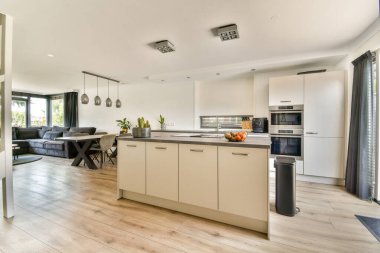 Şık, modern bir mutfak rahat bir oturma odasına bağlanıyor, gösterişli dolaplar ve zarif ışıklandırma, çağdaş yaşam alanları için mükemmel..