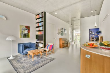 Şık, modern bir iç mekan, rahat bir oturma alanı, kitaplıklar ve canlı bir renk paleti. Tasarımda minimalist estetik ve fonksiyonel dekor yer alıyor..