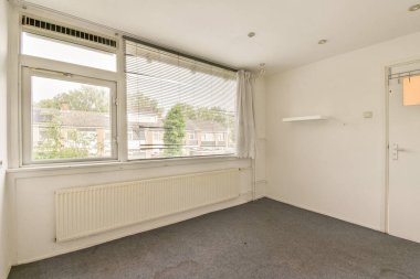 Geniş, parlak bir oda geniş pencereler, minimal dekor ve nötr renk paleti sergiliyor. Modern bir yaşam alanı ya da ofis düzeni için ideal..