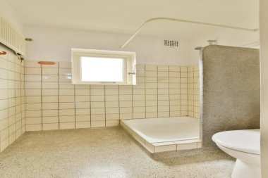 Temiz ve modern bir banyo sergilenen minimalist bir tasarım fayanslı duvarlar, bir duş alanı ve pencereden bol miktarda doğal ışık..