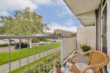 Çok güzel düzenlenmiş bir balkon, rahat koltuklar ve şehir yeşilliği. Sahne, şehir yaşamının ortasında sakin bir açık hava alanı yakalıyor..