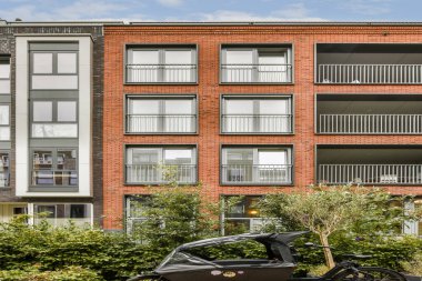 Üste birden fazla balkon ve yeşilliğin yer aldığı, kentsel mimari ve tasarım unsurlarının sergilendiği göz alıcı modern bir bina..