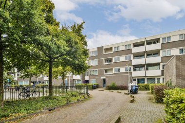 Çağdaş bir apartmanda, bereketli ağaçlar ve sakinler için bakımlı yollar çerçevelenmiş mimari ve doğanın bir karışımı sergileniyor..