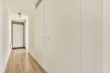 Temiz beyaz duvarları ve şık ahşap zemini olan parlak ve ferah bir koridor iç tasarıma minimalist bir yaklaşım sergiliyor..