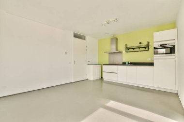 Modern kabinenin yer aldığı geniş bir mutfak ve işlevsellik ve tarz için tasarlanmış canlı yeşil bir aksan duvarı..