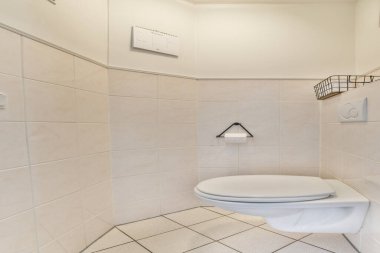 Pürüzsüz ve modern bir banyo. Hafif fayanslı temiz bir tasarım ve minimalist düzene entegre edilmiş bir tuvalet. Sakin ve işlevsellik hissi uyandırıyor..