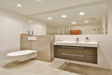 Gösterişli ve çağdaş banyo. Minimalist tasarım elementleri, şık eşyalar ve geniş ışıklandırma, davetkar bir alan yaratıyor..