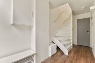 Modern mimari, temiz çizgiler ve minimalist dekorun yer aldığı gösterişli ve parlak bir koridor. İyi ışıklandırılmış alanda şık bir merdiven ve fonksiyonel depolama birimleri var..