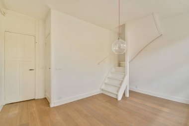 Parlak, minimalist bir iç mekan merdiven, ahşap döşeme ve kolye ışığı vurgulu sadelik ve modern tasarım sergileniyor..