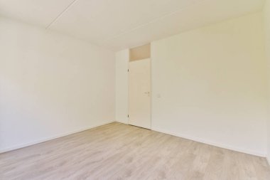 Beyaz duvarları ve ahşap zemini olan geniş, minimalist boş bir oda, çeşitli iç tasarım olanakları ve yenilemeler için ideal..