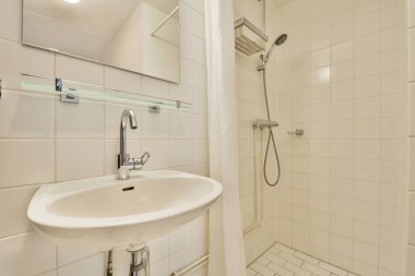 Zarif ve şık bir banyo. Temiz beyaz fayanslar ve basit armatürler ile modern bir duş düzeneği var. Minimalizm ve işlevselliği vurguluyor..