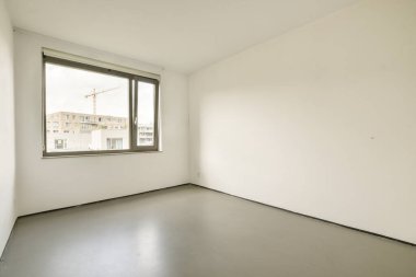 Geniş, minimumda döşenmiş, geniş bir penceresi olan bir iç oda. Tarafsız tonlar ve basitlik sakin bir atmosfer yaratır. Modern yaşam için mükemmel..