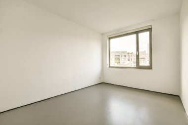 Parlak, seyrek döşenmiş, geniş pencereli, doğal ışığın boşluğu doldurmasını sağlayan bir oda. Duvarlar sade ve renkler tarafsız..