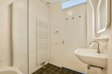 Minimalist tasarımı olan gösterişli bir banyo, temiz çizgiler, beyaz fayanslar ve çağdaş görünüş için modern eşyalar..