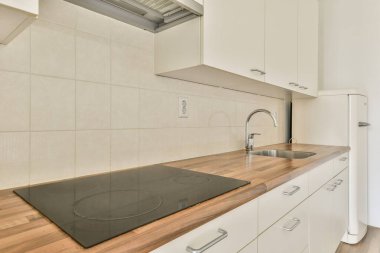 Gösterişli ve minimalist mutfak, ahşap tezgah, dahili soba ve parlak dolap. Bu alan, çağdaş biçim ve işlevselliği gösterir.