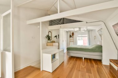 Yumuşak mobilyalar, ahşap döşemeler ve pencerelerden içeri doğru akan doğal ışık içeren sıcak tasarlanmış minimalist bir yatak odası, sakin bir atmosfer yaratır..