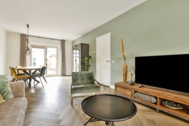 Mobilyaların, doğal ışığın ve minimalist tasarımın bulunduğu modern bir oturma odası rahat ve davetkar bir atmosfer yaratıyor. Rahatlamak ve eğlenmek için ideal..