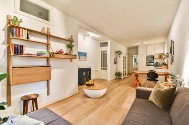 Minimalist mobilyaların, sıcak tonların ve dekoratif bitkilerin bulunduğu rahat ve modern bir yaşam alanı, rahatlama için sakin bir atmosfer yaratıyor..