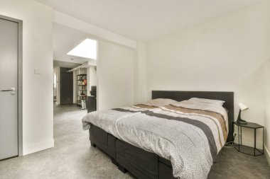 Çağdaş bir yatak odası, dokulu bir battaniyesi, minimalist bir dekoru ve yumuşak doğal bir atmosferi olan düzgün bir yatak odası..