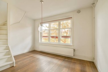 Geniş bir pencere ve basit bir dekorun yer aldığı parlak ve havadar bir iç mekan. Tasarım, doğal ışık ve temiz çizgileri vurguluyor ve sakin bir atmosfer yaratıyor..